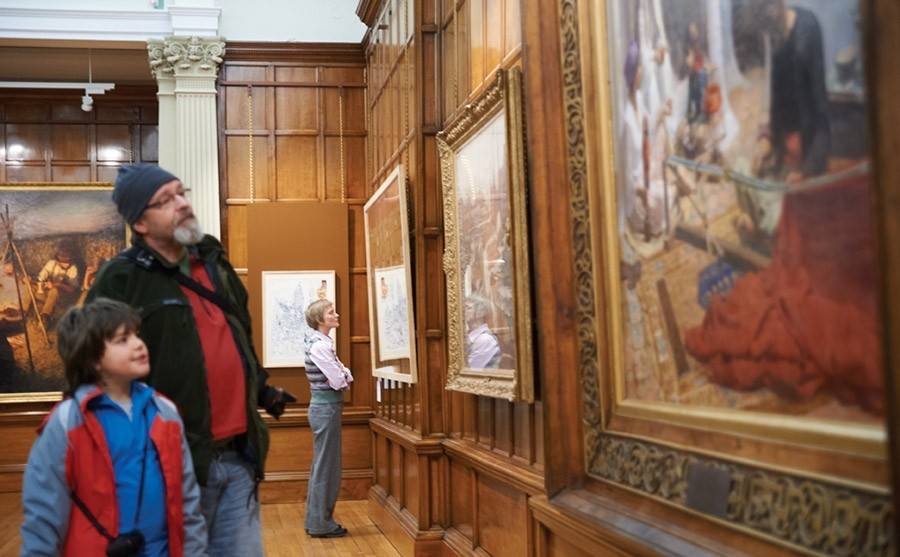 Man & child looking at a selection of paintings in the Cartwright Hall art gallery