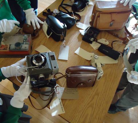 Kids in museums looking at old cameras on a table