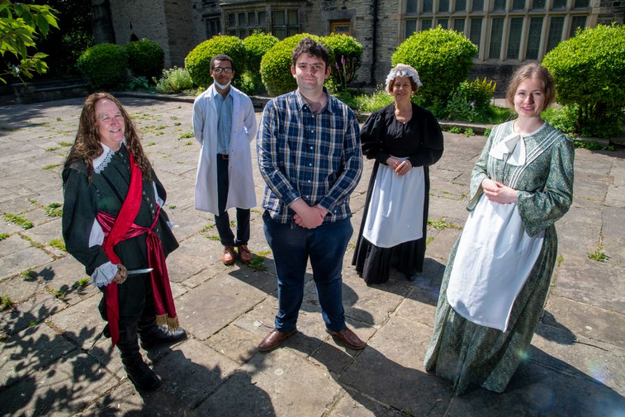 Daniel surrounded by members of the cast in the grounds of the hall