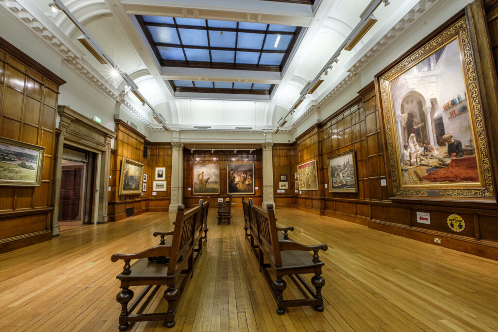 the interior of a panelled gallery within Cartwright.  Large paintings are mounted on the wall