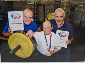 Photograph of Pilling, Brown and Bennett, with the certificates Stephen won at the IBSA International Blind Sports Federation Championships in Powerlifting, 2002