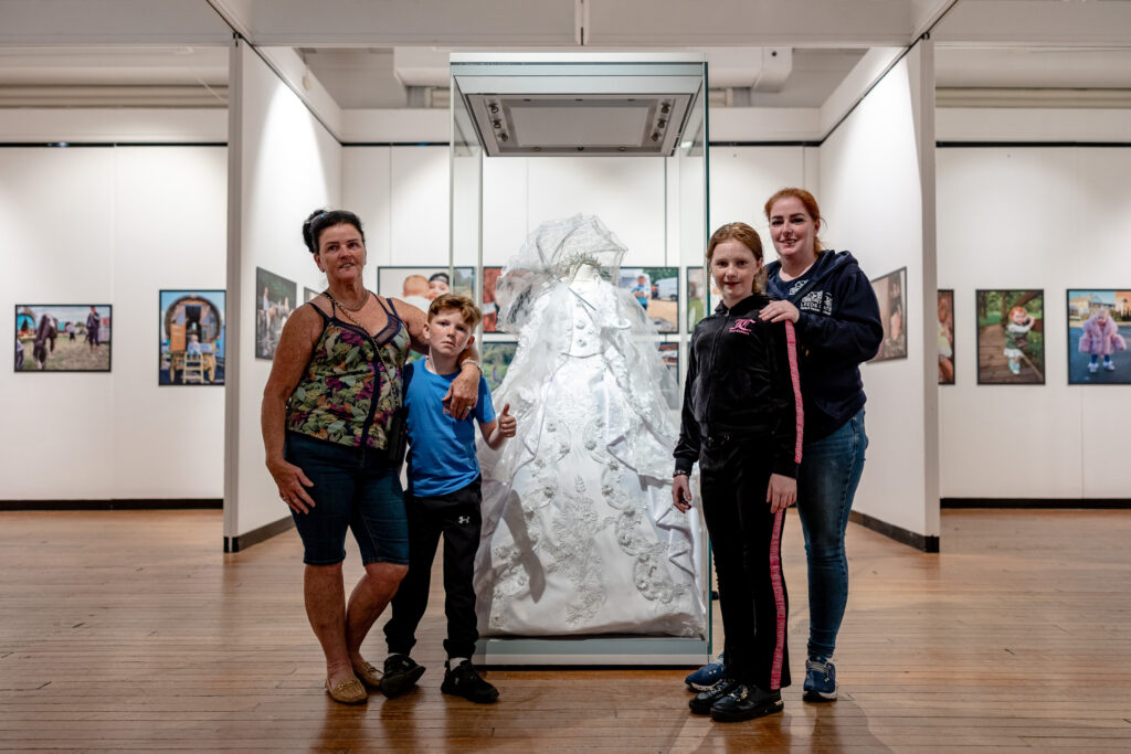 Kathleen and her children in front of a dress in the exhibition