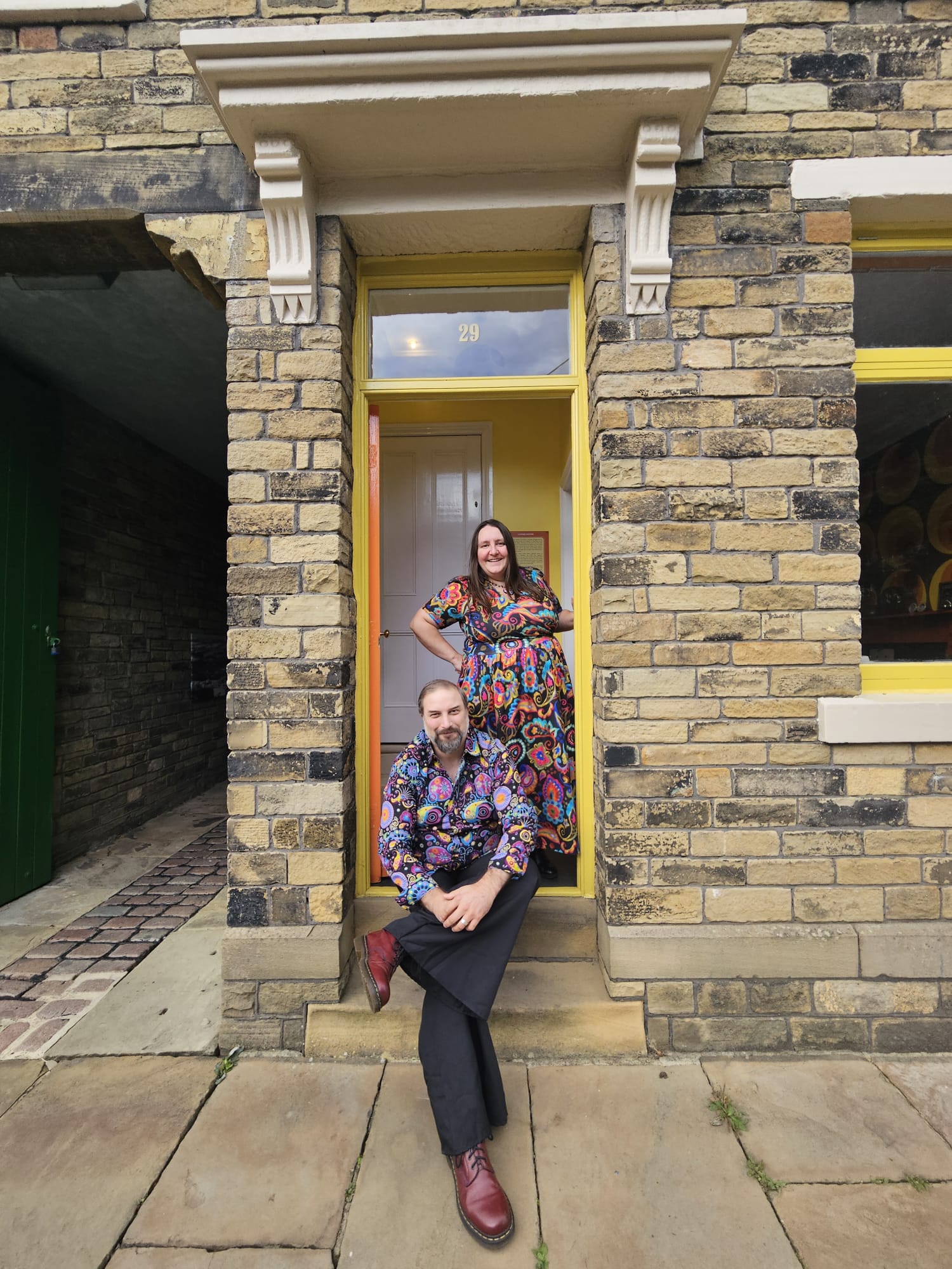 image of a man and a woman in 70s style clothes in the doorway to the back to back