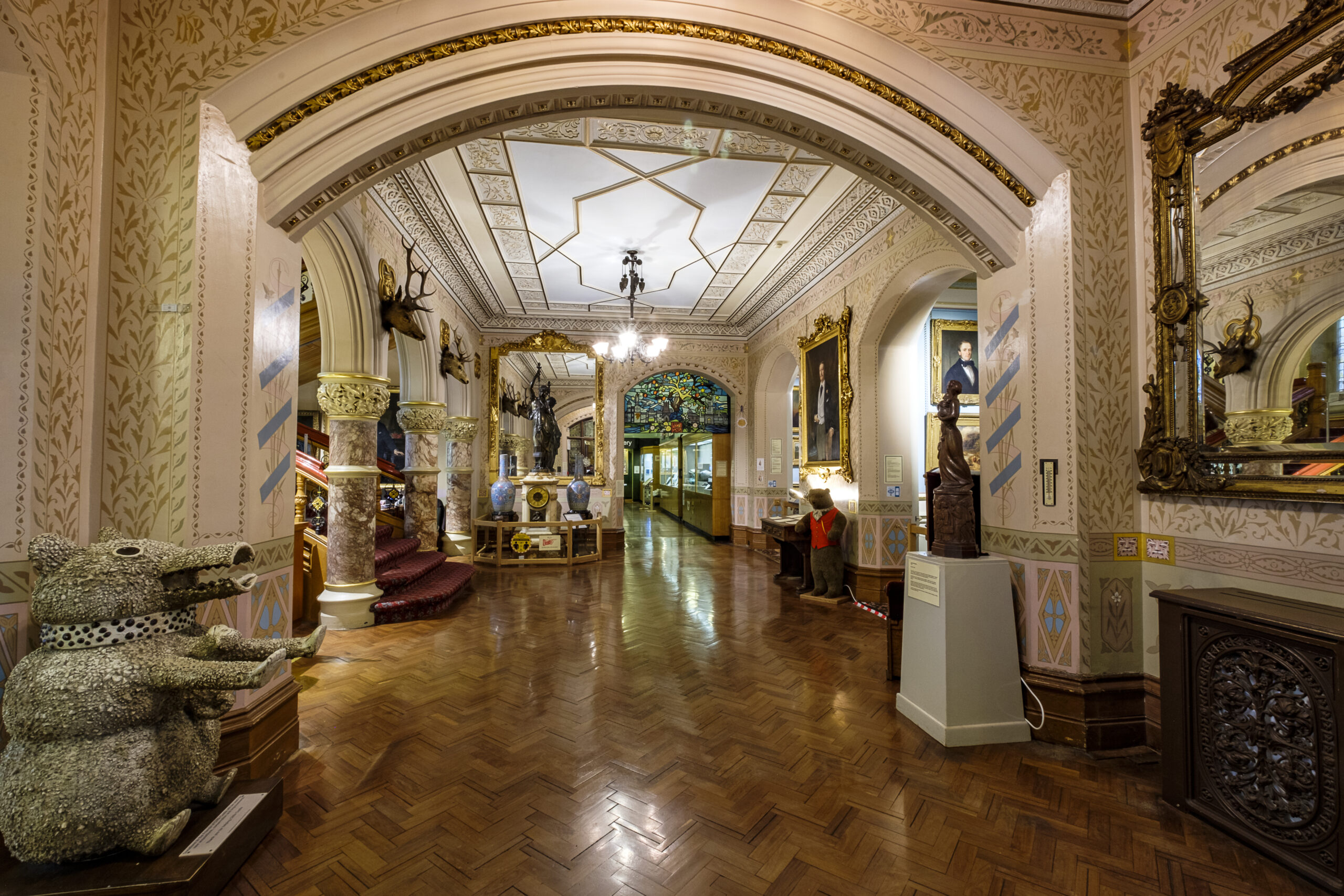 entrance hallway of Cliffe Castle - ornately painted walls, portraits on the wall and various objects