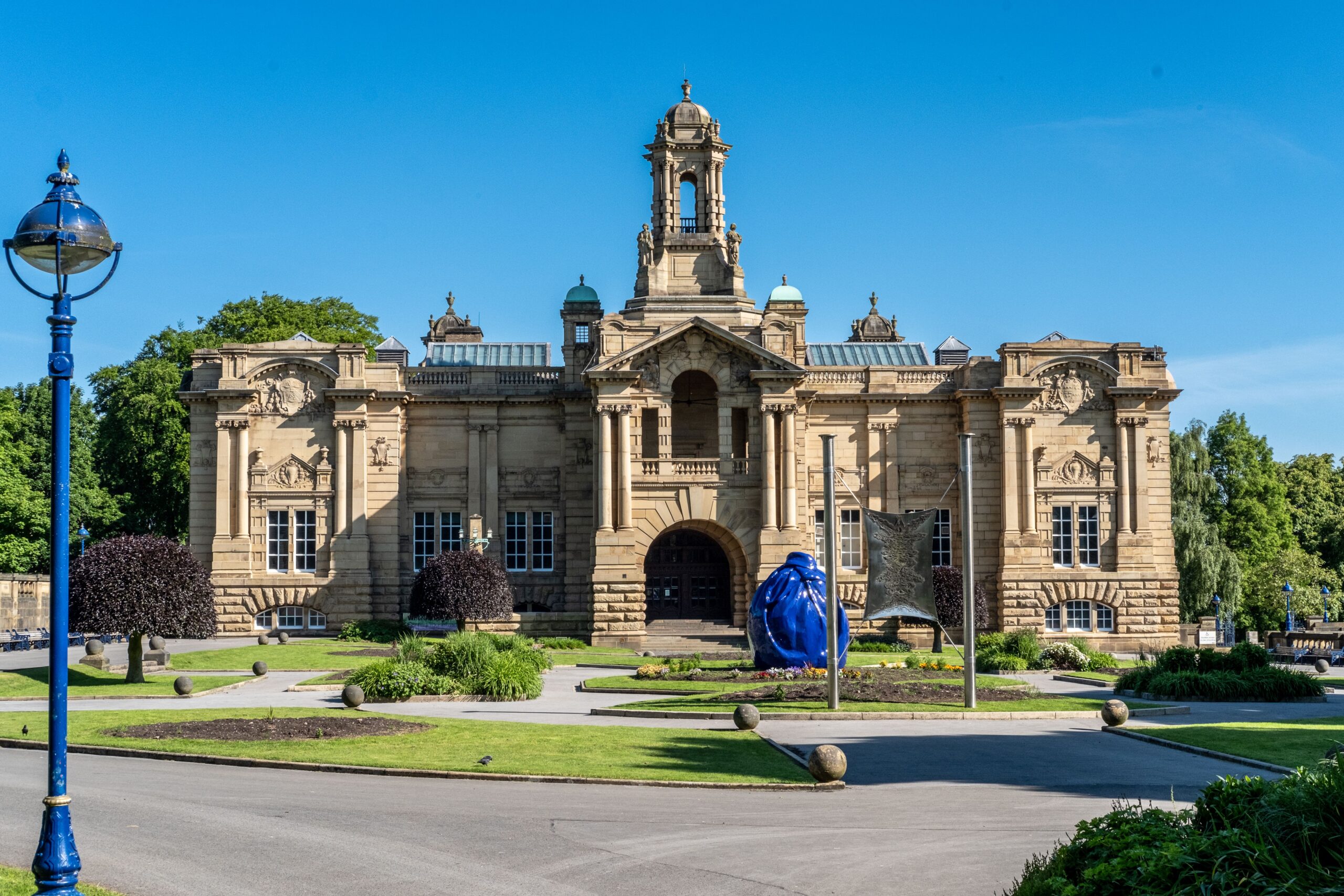 Cartwright Hall in the sunshine, with blue skies, and a blue sculpture in front