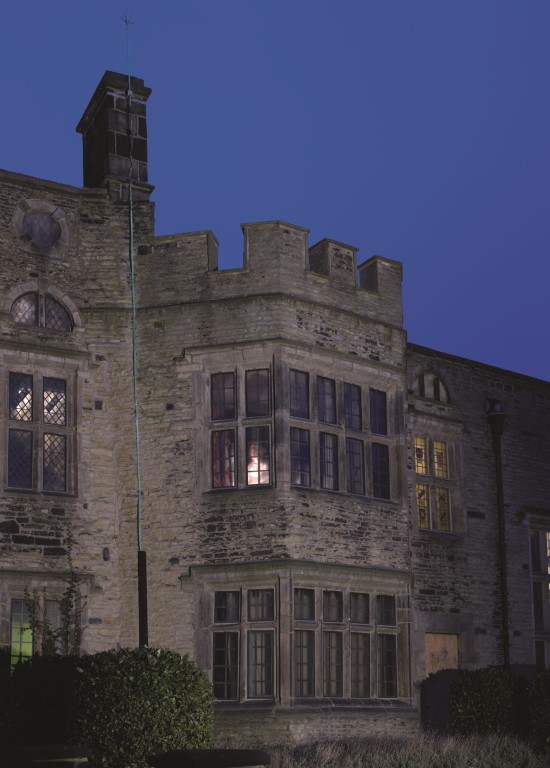 spooky image of Bolling Hall at night with a ghostly figure in the window