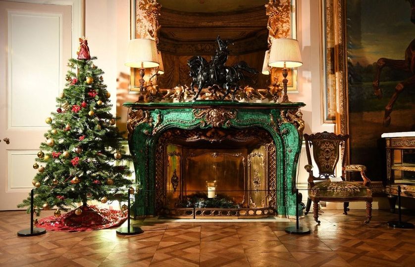 Christmas tree to the side of a big green fireplace