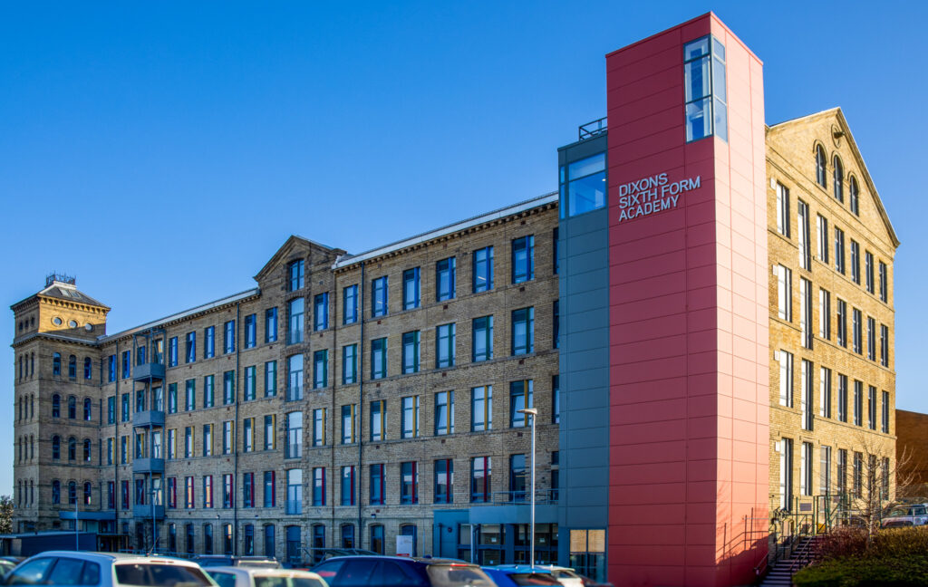 Mill building, fully glazed and restored, one tower clad in red and gray saying 'Dixons Sixth Form Academy