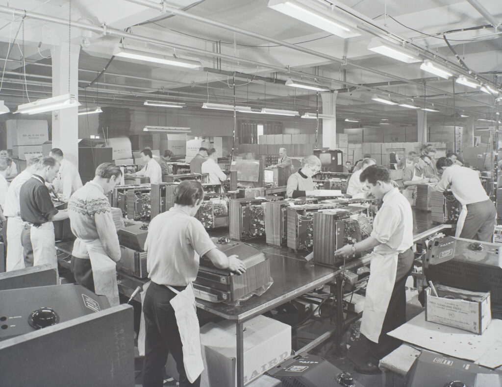 B&W photo of men boxing up televisions