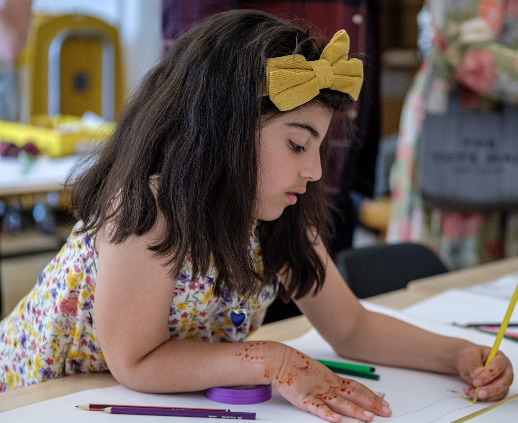 Young girl drawing, henna design on side.