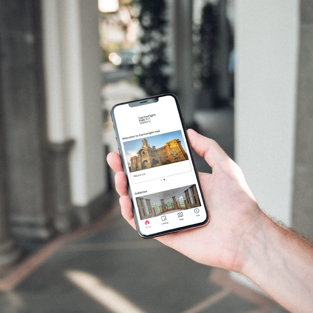 a hand holding a mobile phone showing the bloomberg app - on screen is Cartwright Hall Art Gallery guide