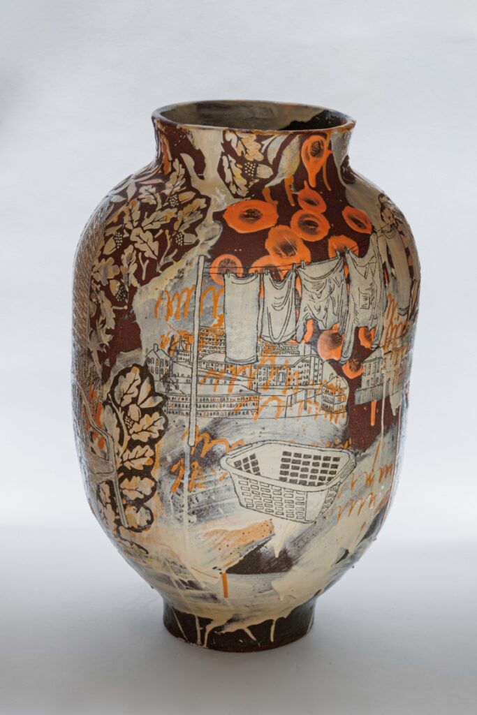 Ceramic vase with a orangy-brown base colour, decorated with images of gardening implements and allotment imagery, washing line and basket and other garden/allotment imagery.  In tones of cream, whte and orange