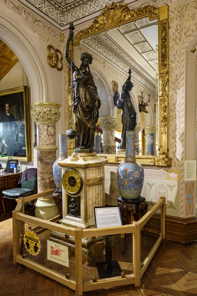 a view of a clock, behind which is a mirror covered in musical imagery