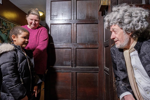 Family listening to Abraham Sharpe - a man in 18th century dress and long grey wig