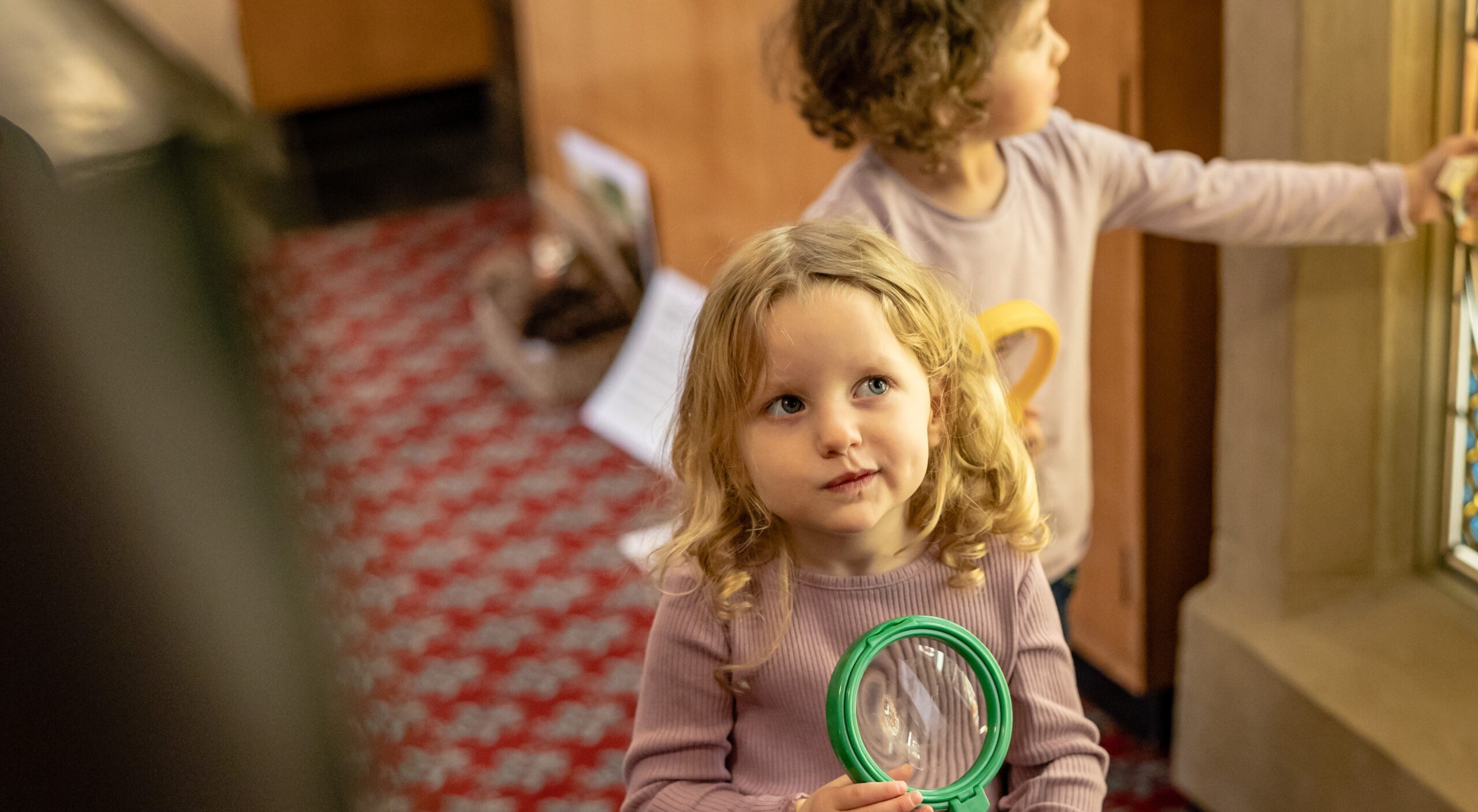 A little girl in a museum holding a magnifying glass