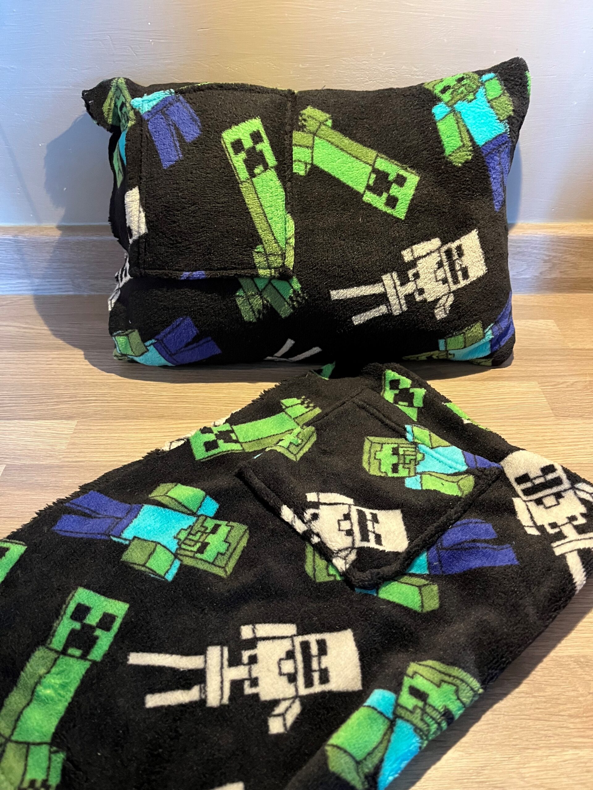 fuzzy black and green cushion made with fabric from the dressing gown in front.