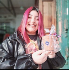 a young woman with pink hair smiling at the camera