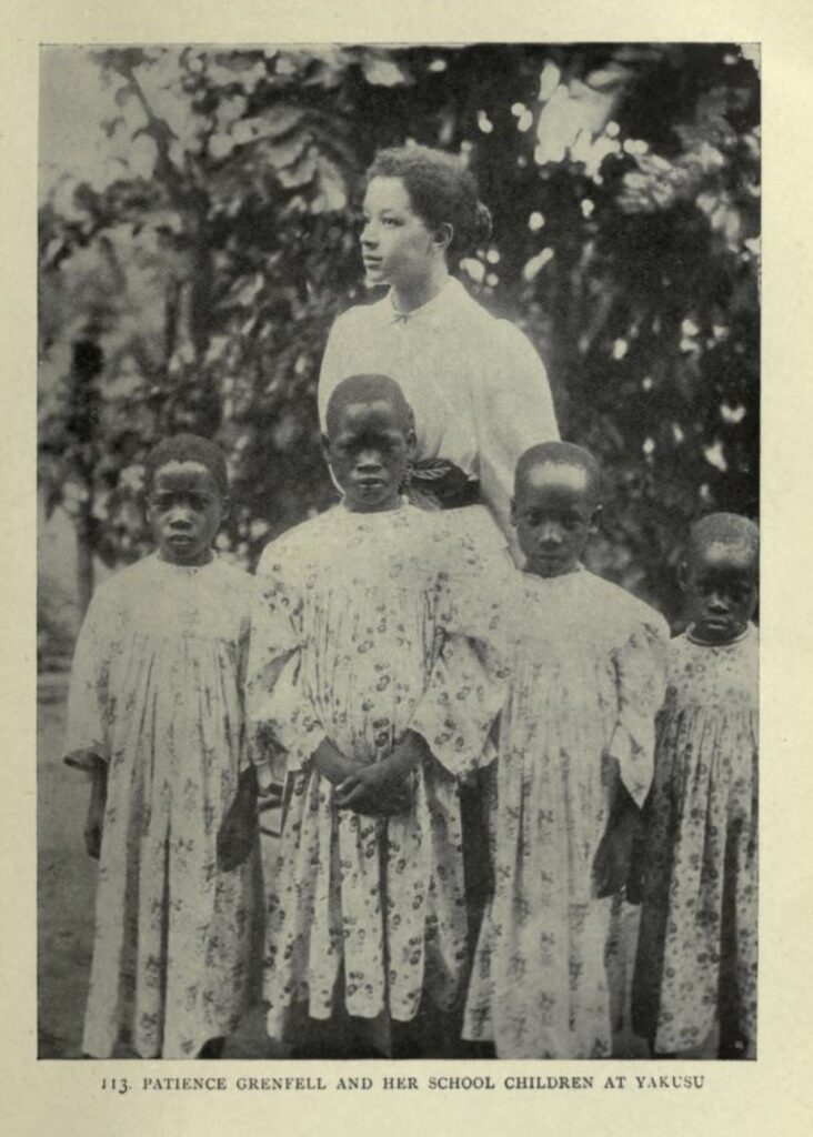 a young mixed race woman stood behind a group of young black children