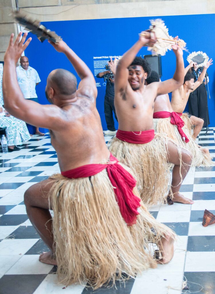 a group of men in traditional polynesian outfits dancing .