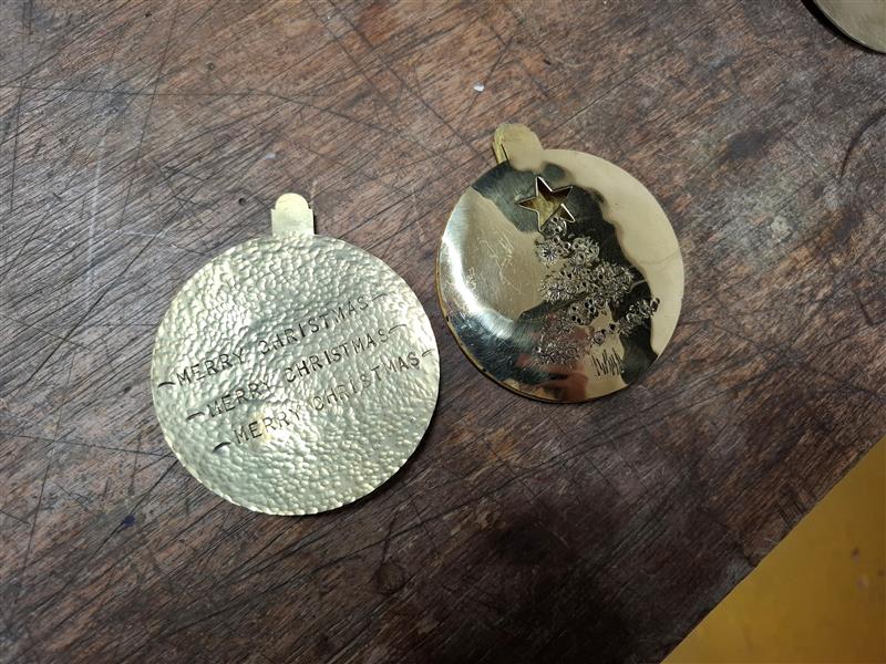 brass disc shaped like baubles, with 'Merry Christmas' stamped on them