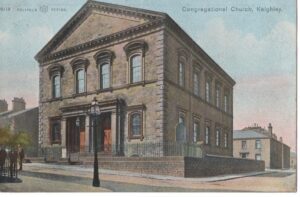 Vintage postcard, a color illustration of the Congregational Church in Keighley, a large stone building with tall arched windows, a central entrance with columns, and a streetlamp in front.
