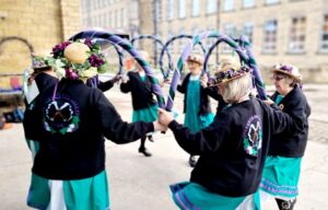 a group of women morris dancing in front of a mill