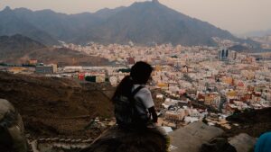 photo of a person (details unclear as figure has back to viewer and is in shadow, looking over a large settlement