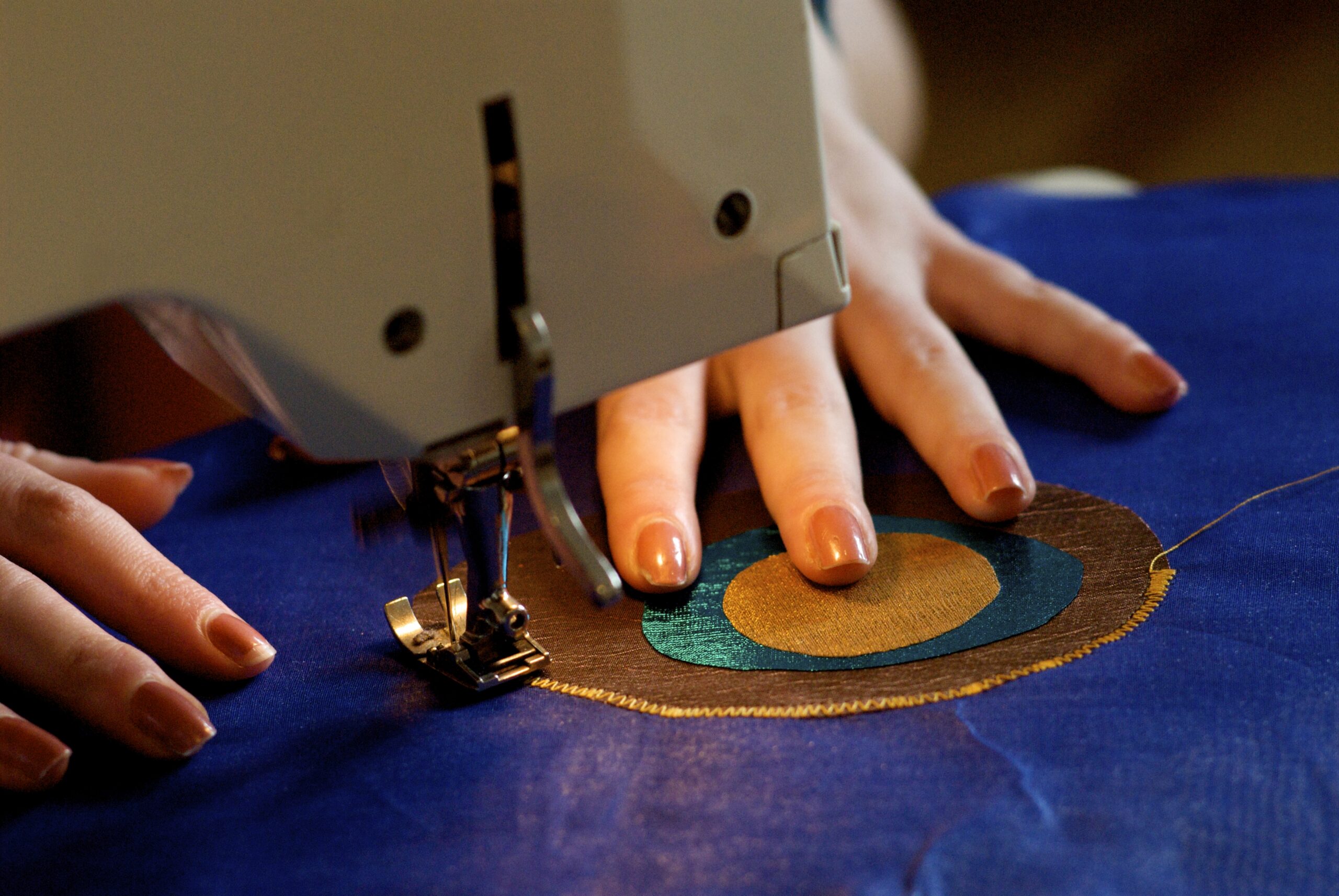 view of a sewing machine with hands and fabric