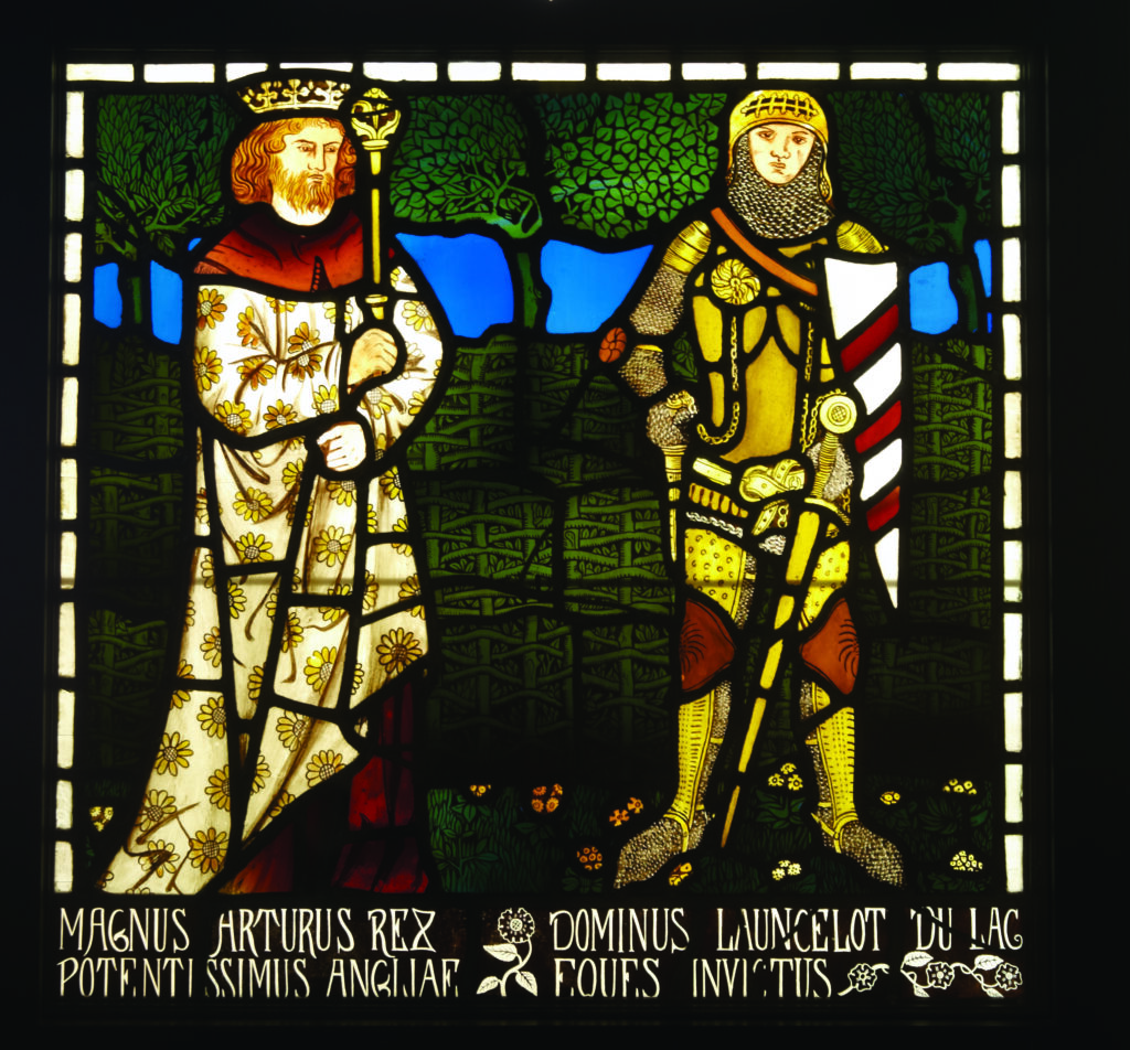 Here’s alt text for the third stained‑glass panel, keeping it concise, objective, and aligned with accessibility best practice.

⚔️ Alt text: Panel 3 (Arthur and Lancelot)
Stained‑glass panel showing King Arthur and Sir Lancelot standing side by side. Arthur wears a crown and a white robe patterned with yellow flowers, holding a scepter. Lancelot stands in golden armor and chainmail, holding a sword and a shield with red‑and‑white diagonal stripes. Behind them are green leaves and a blue sky, with a decorative floral border at the bottom. Latin text identifies them as King Arthur and Sir Lancelot du Lac.
