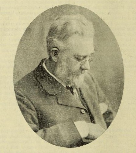 This is a black and white image of a side profile of Lees as an older man. He is looking down towards the right. He has white hair and a white beard, wearing a suit and a pair of small round glasses
