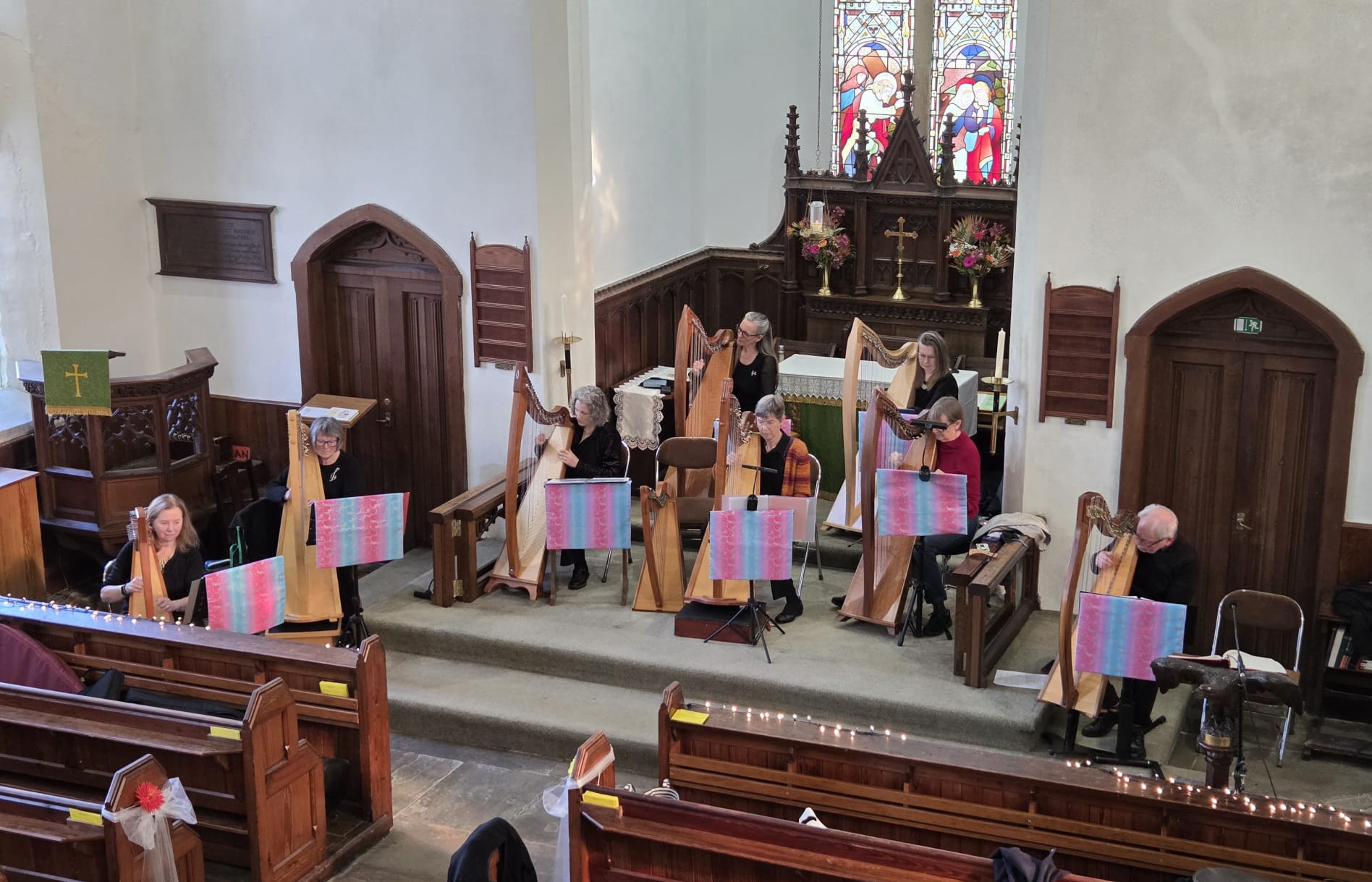 Harpists performing in a church, seated in a semicircle near the altar with their harps.